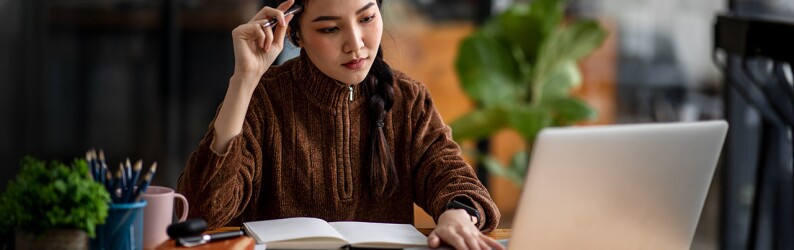 Woman studies with books and a laptop on the desk in front of her