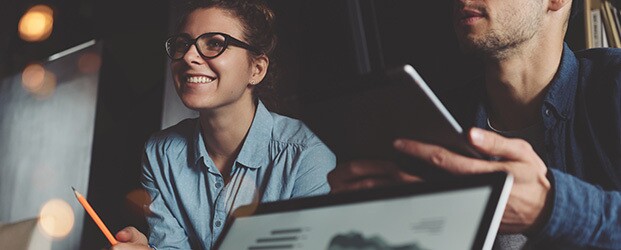 College students in animated discussion, using laptop and tablet computers
