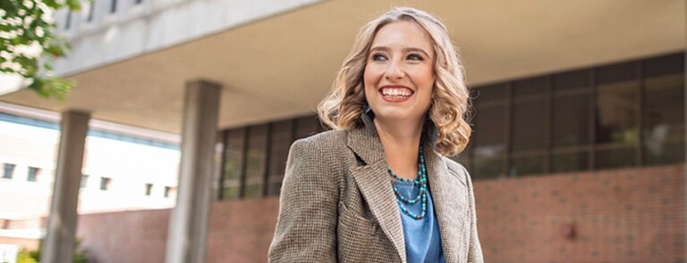 Chico student smiling in front of building on campus