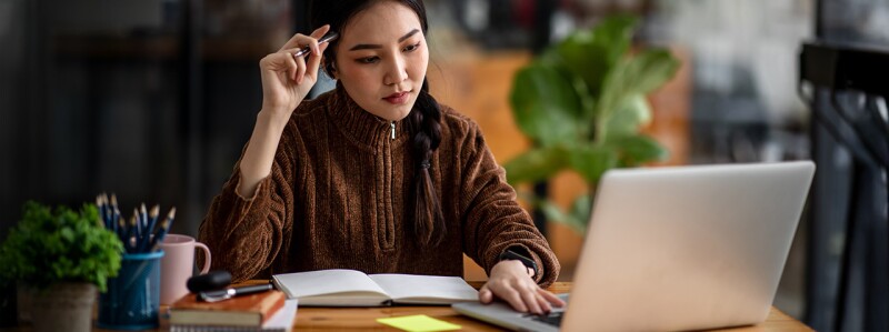 Woman studies with books and a laptop on the desk in front of her