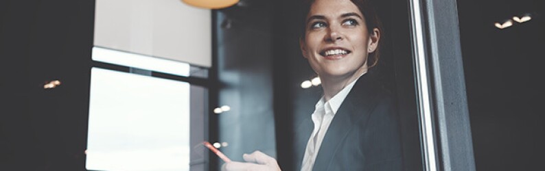 Woman in business attire smiles in a modern office setting
