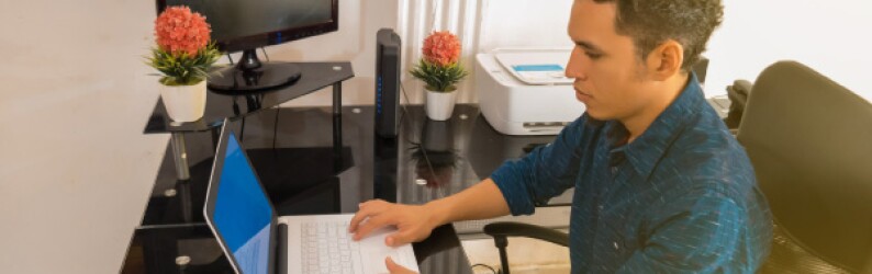 Young Guy Working on Laptop in Home Office