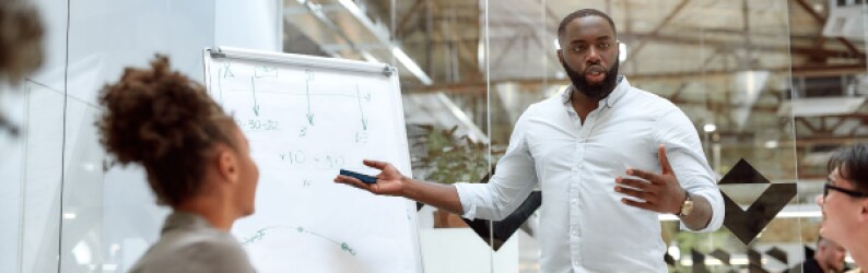 man presenting in front of crowd with oversized paper glass wall behind him