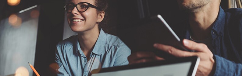 College students in animated discussion, using laptop and tablet computers