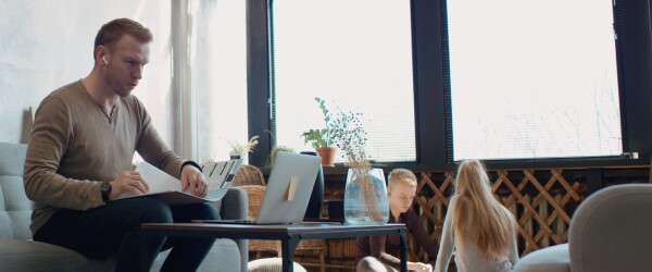 Father works on school work with children in living room