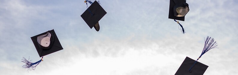 Four graduation caps flying in the air.