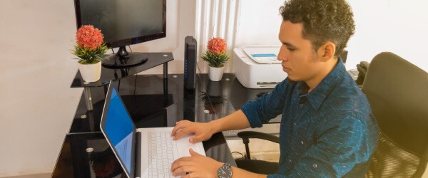 Young Guy Working on Laptop in Home Office