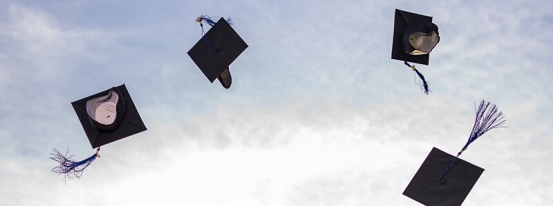 Four graduation caps flying in the air.
